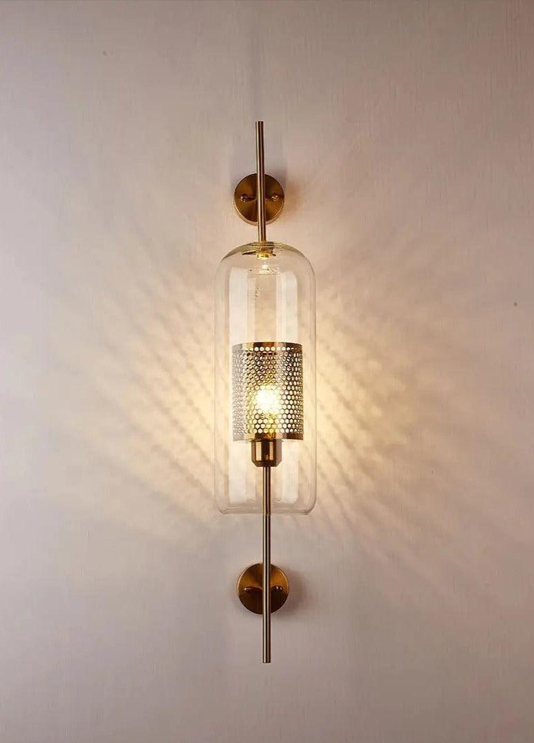 Alegria gold glass wall sconce flanking a bathroom mirror, casting warm light
