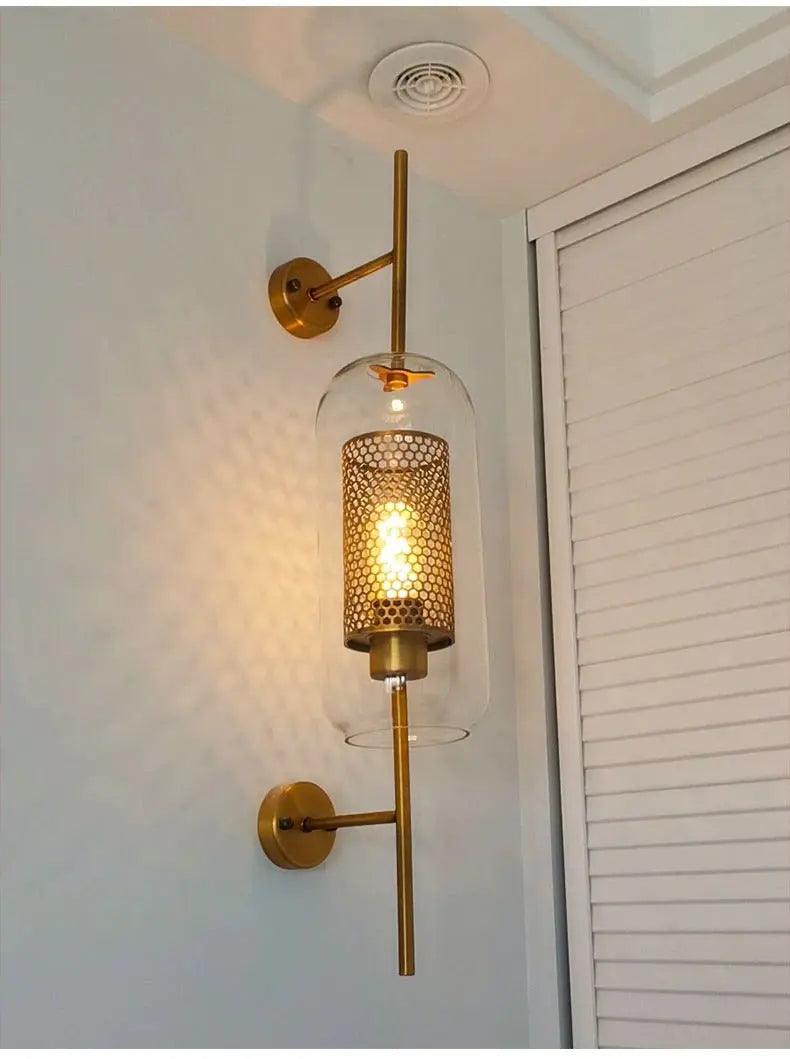 Alegria gold glass wall sconce flanking a bathroom mirror, casting warm light