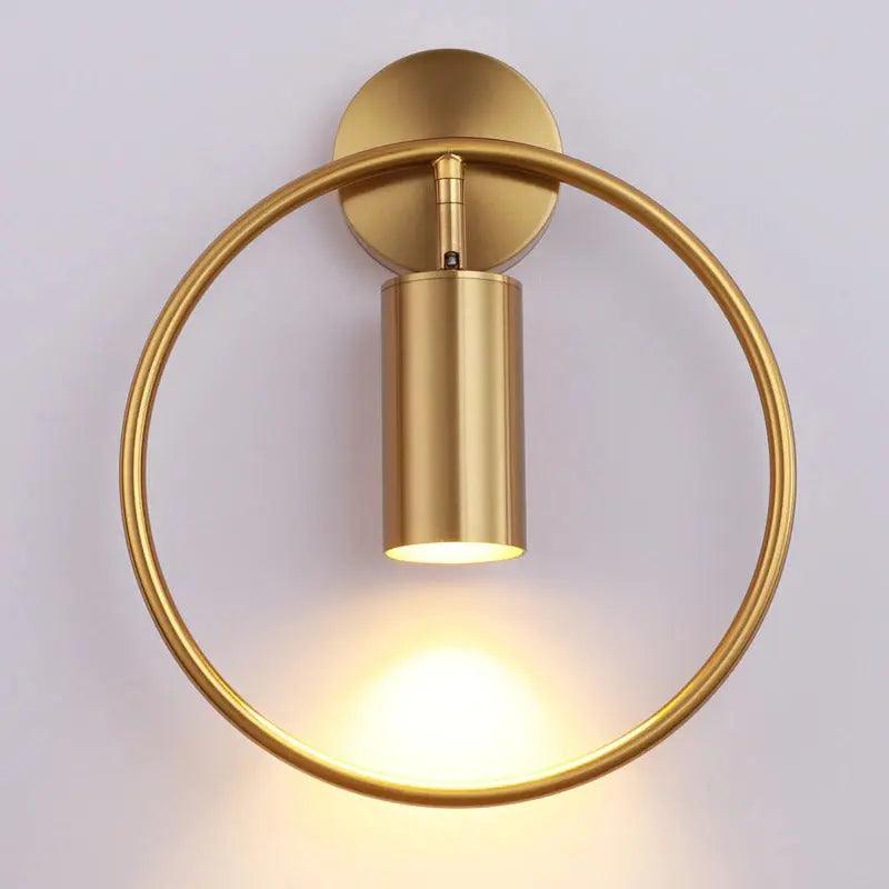 Benthe gold post-modern wall sconce on a white wall in a living room