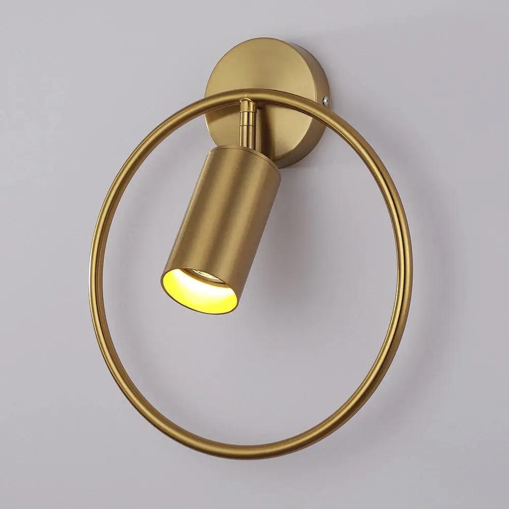 Benthe gold post-modern wall sconce on a white wall in a living room
