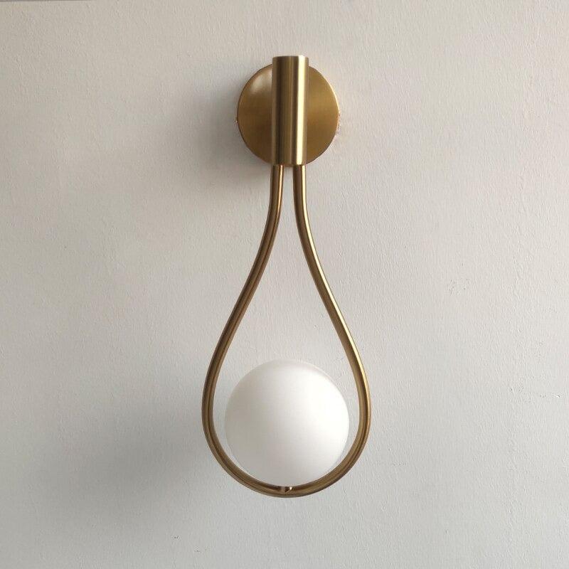 Livi gold Nordic wall sconce mounted beside a bed in a minimalist bedroom