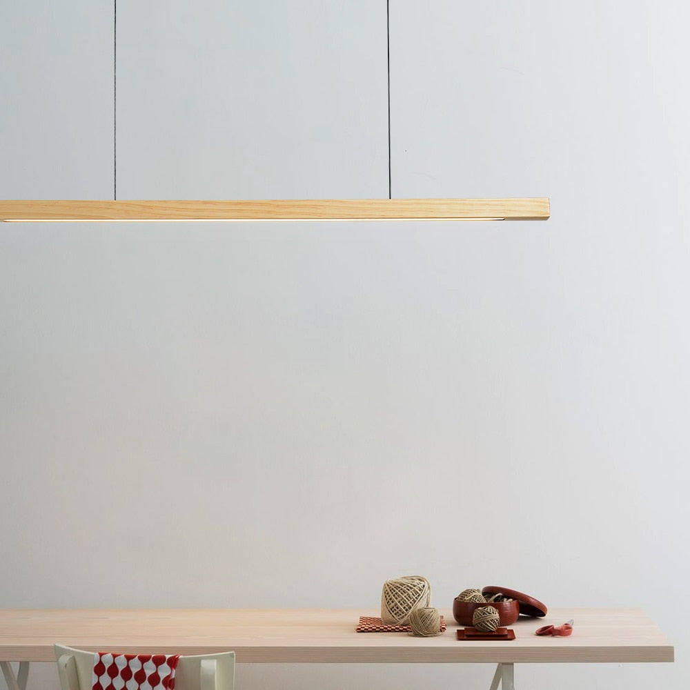 Lindö pine wood dining pendant light hanging low above a long dining table in a Nordic interior