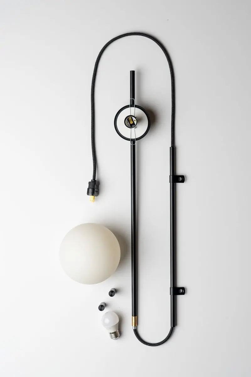 Sol Nordic plug-in wall sconce in black mounted in a living room beside a sofa
