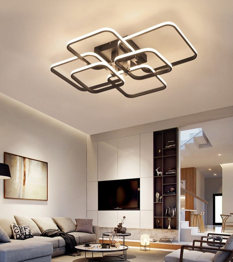 Quadrilateral geometric LED ring chandelier in white, illuminated in a living room with high ceilings