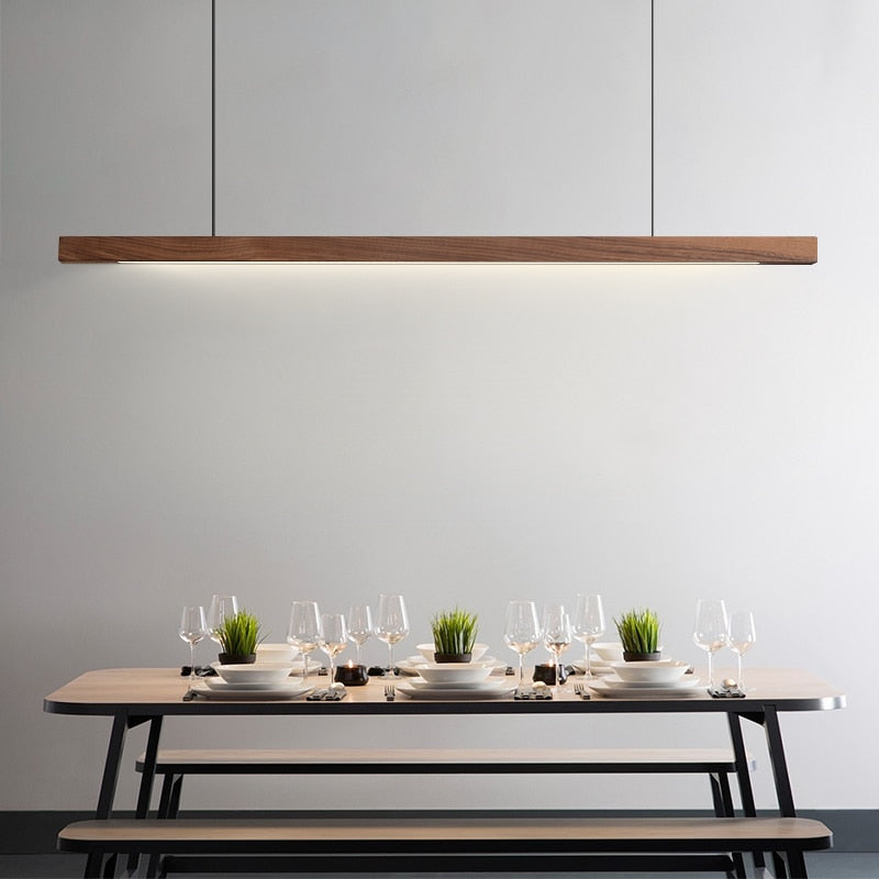 Lindö pine wood dining pendant light hanging low above a long dining table in a Nordic interior