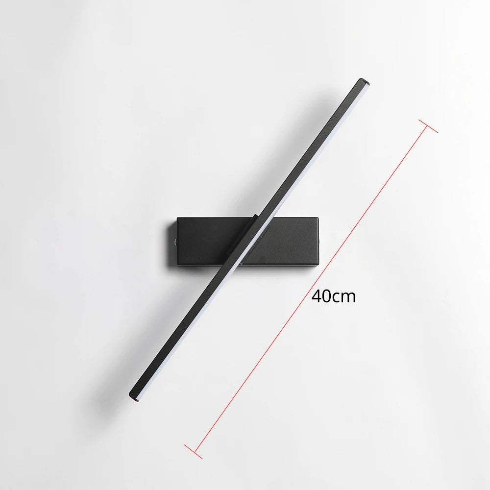 Arc 330-degree adjustable LED bedside wall lamp in black aluminium beside a bed with open book