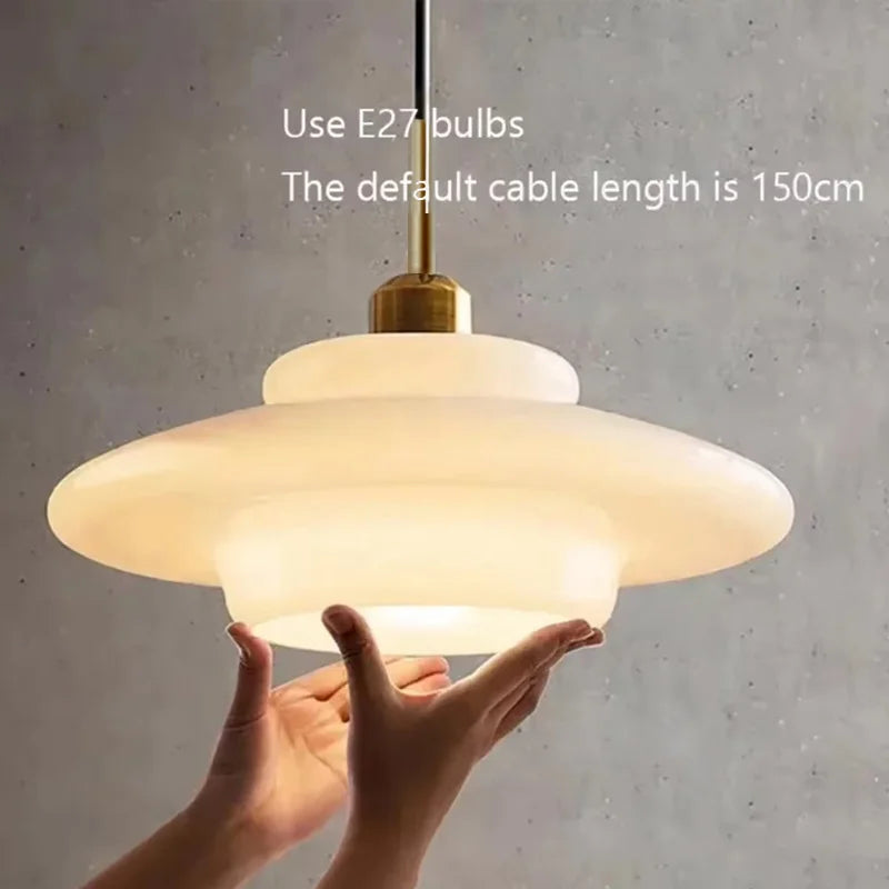 Opal milk glass pendant light hanging above a dining table, casting a soft warm glow