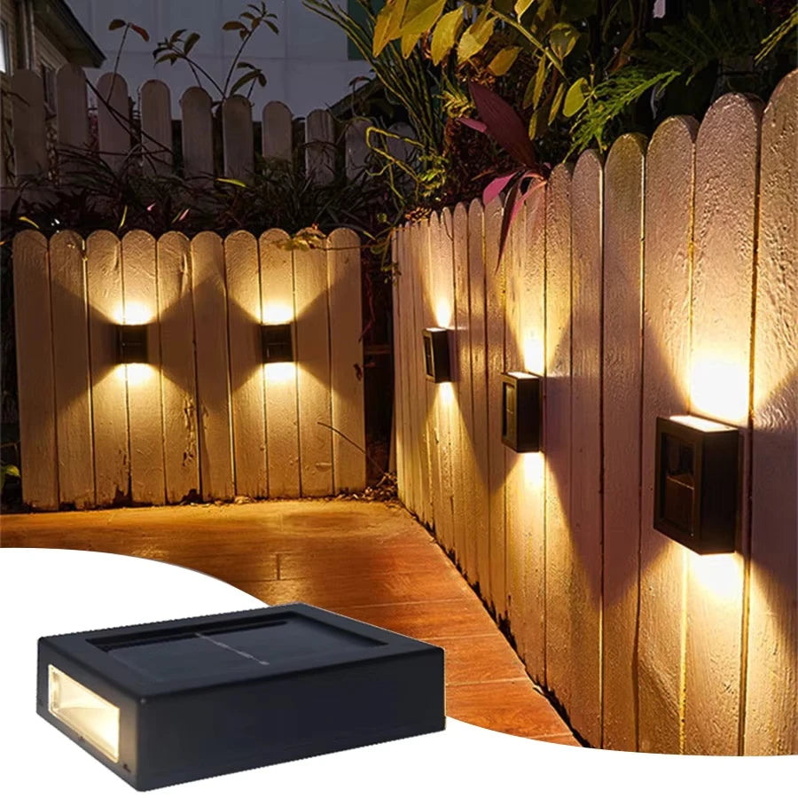 Solstice solar wall light mounted on a garden fence, illuminated at dusk