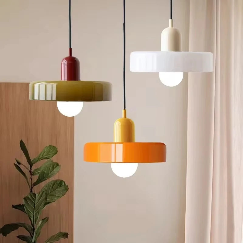 Bauhaus multi-pendant glass chandelier with orange shades hanging above a dining table in a café