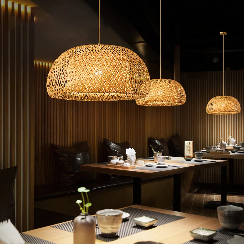 Wren handcrafted woven bamboo pendant light hanging above a wooden dining table in a warm interior
