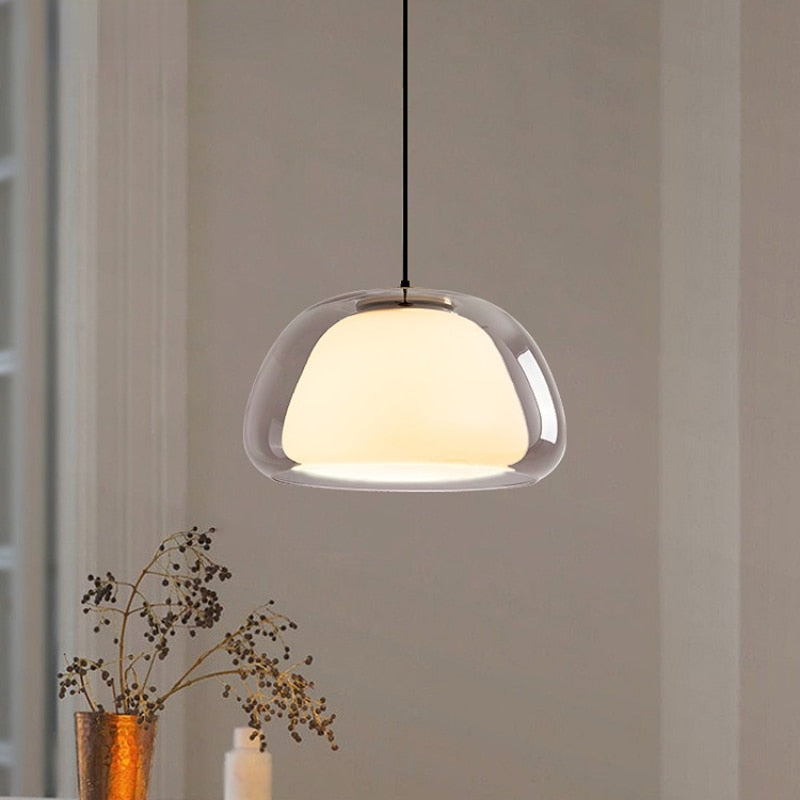 Amba clear jelly globe pendant light with gold fitting hanging above a dining table