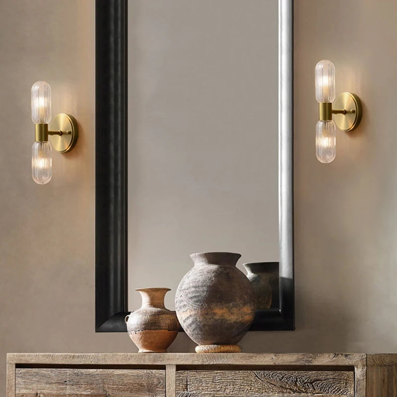 Harlow gold glass wall sconce with copper arm mounted in a living room beside an armchair