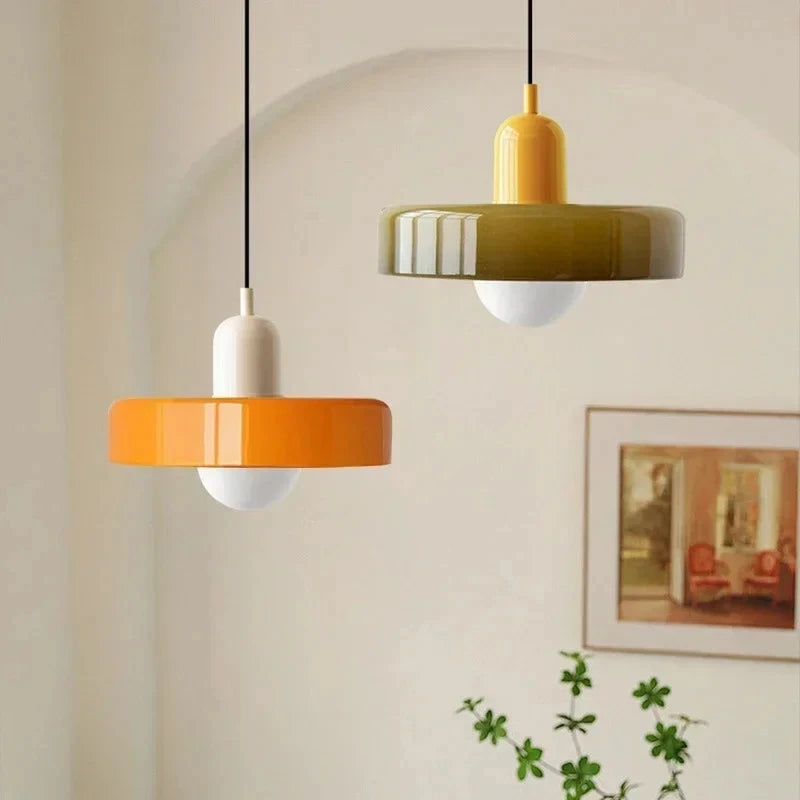 Bauhaus multi-pendant glass chandelier with orange shades hanging above a dining table in a café
