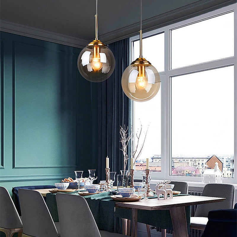 Orla amber glass and metal pendant light hanging above a bedside table in a Nordic-style bedroom