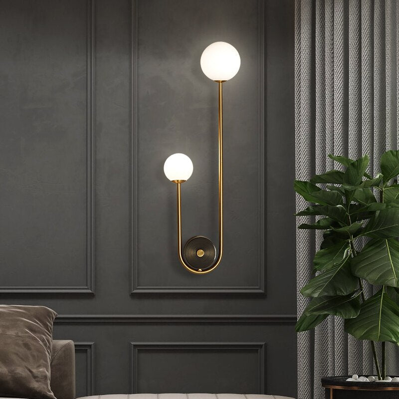 Amalia twin-arm gold Nordic wall sconce with white glass shades flanking a dining room mirror