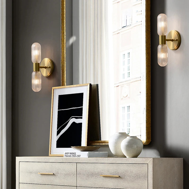 Harlow gold glass wall sconce with copper arm mounted in a living room beside an armchair