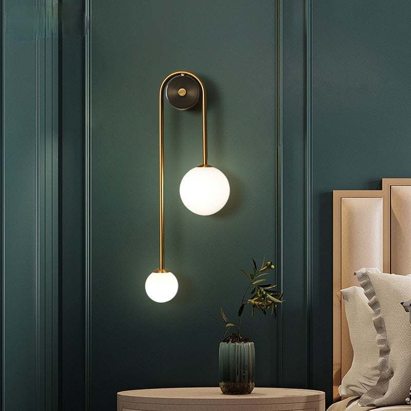 Amalia twin-arm gold Nordic wall sconce with white glass shades flanking a dining room mirror