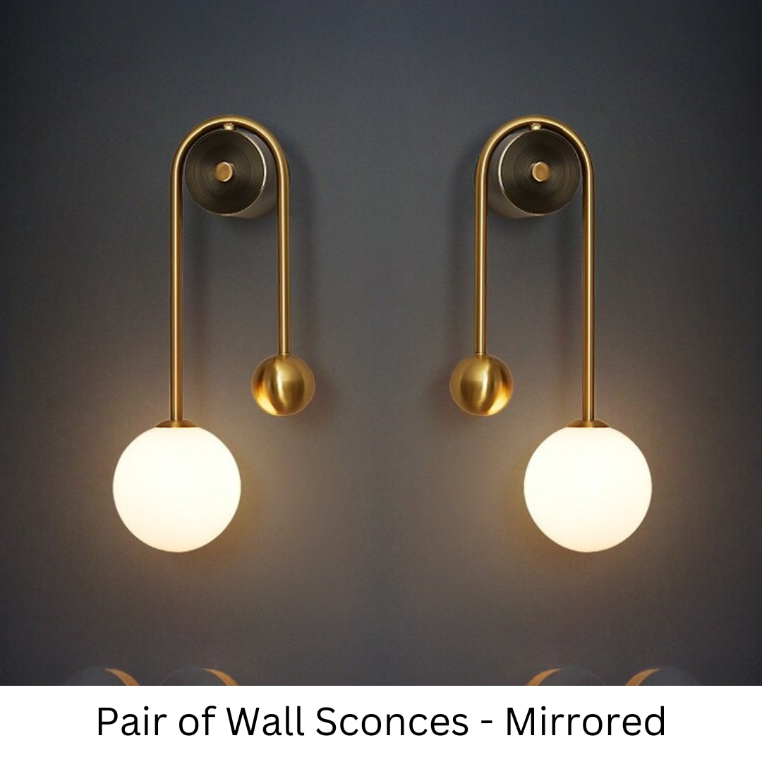 Amalia twin-arm gold Nordic wall sconce with white glass shades flanking a dining room mirror