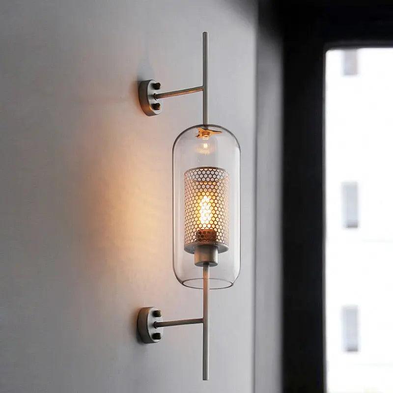 Alegria gold glass wall sconce flanking a bathroom mirror, casting warm light