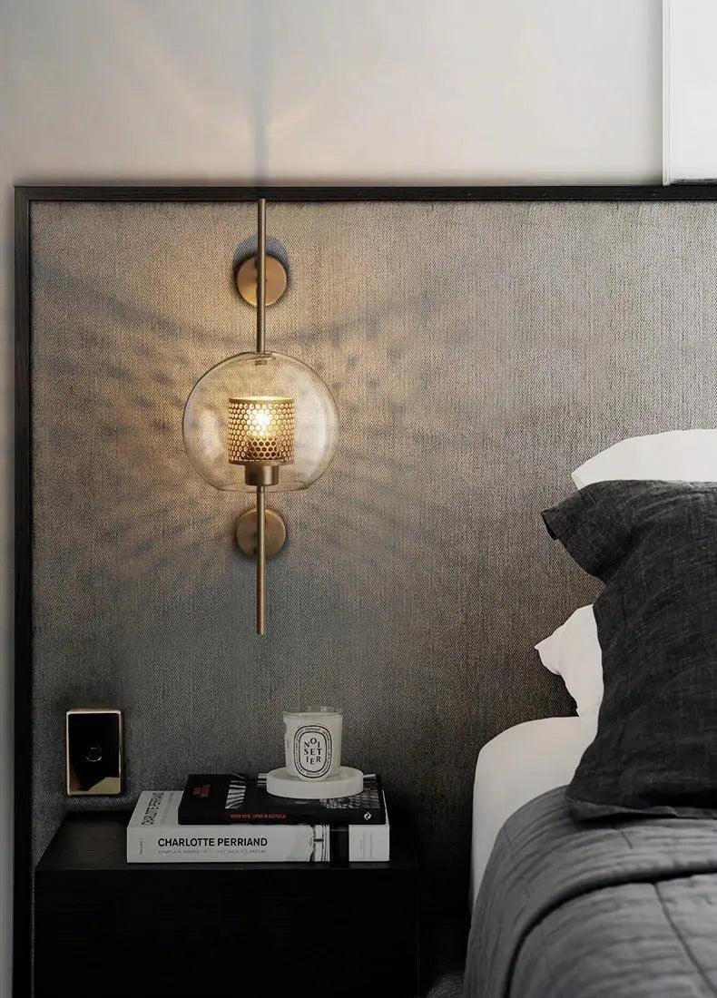 Alegria gold glass wall sconce flanking a bathroom mirror, casting warm light