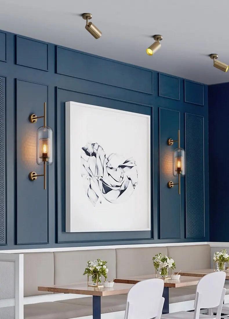 Alegria gold glass wall sconce flanking a bathroom mirror, casting warm light