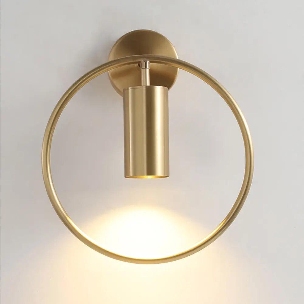 Benthe gold post-modern wall sconce on a white wall in a living room