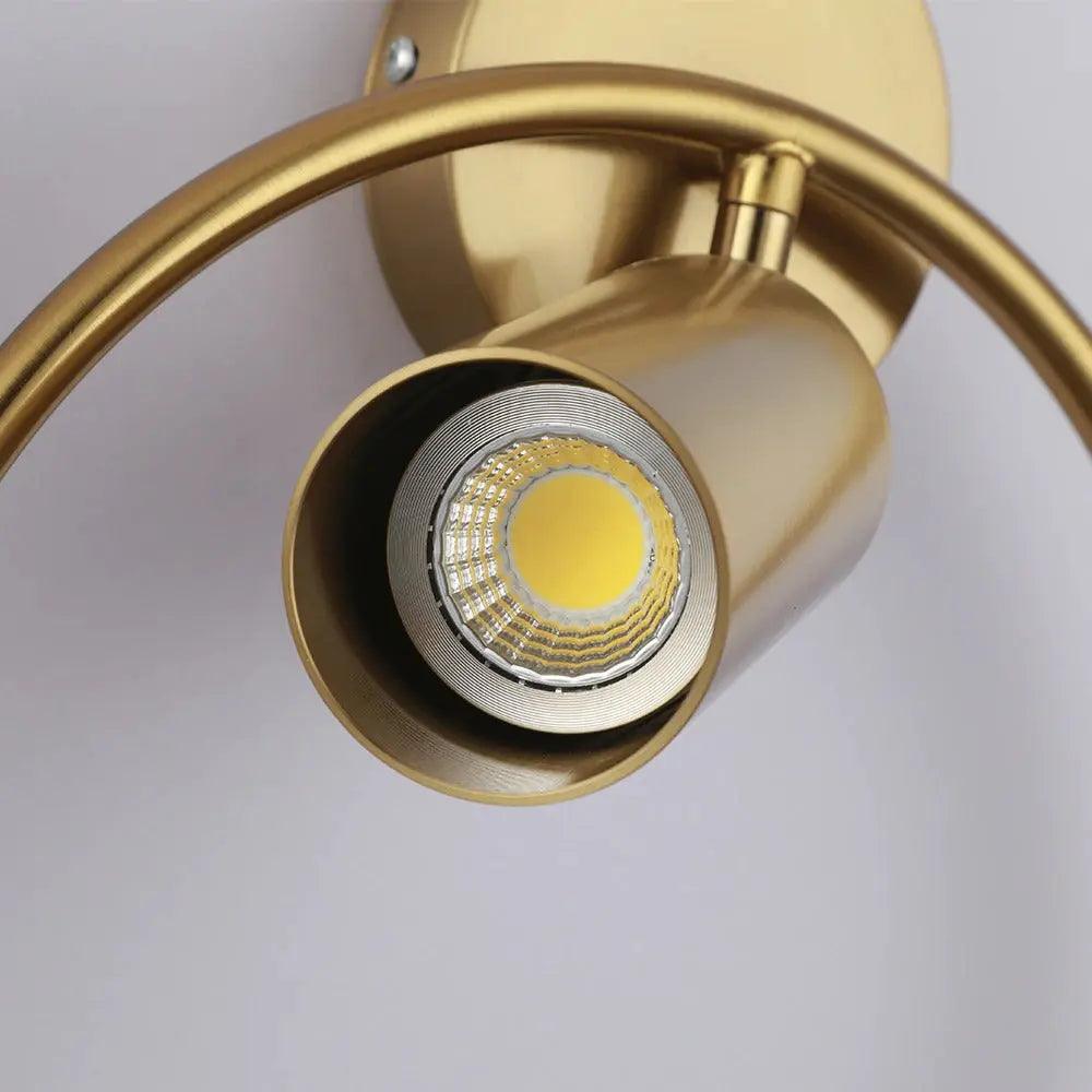 Benthe gold post-modern wall sconce on a white wall in a living room