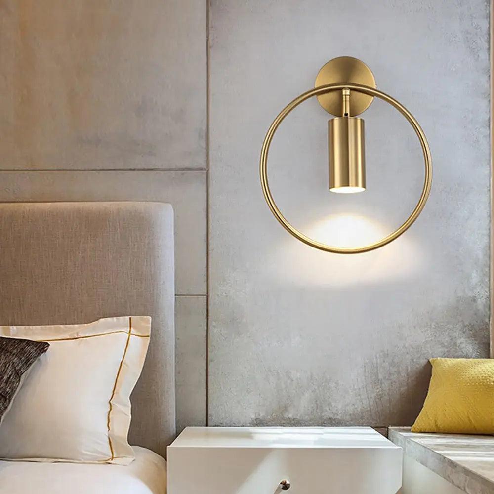 Benthe gold post-modern wall sconce on a white wall in a living room