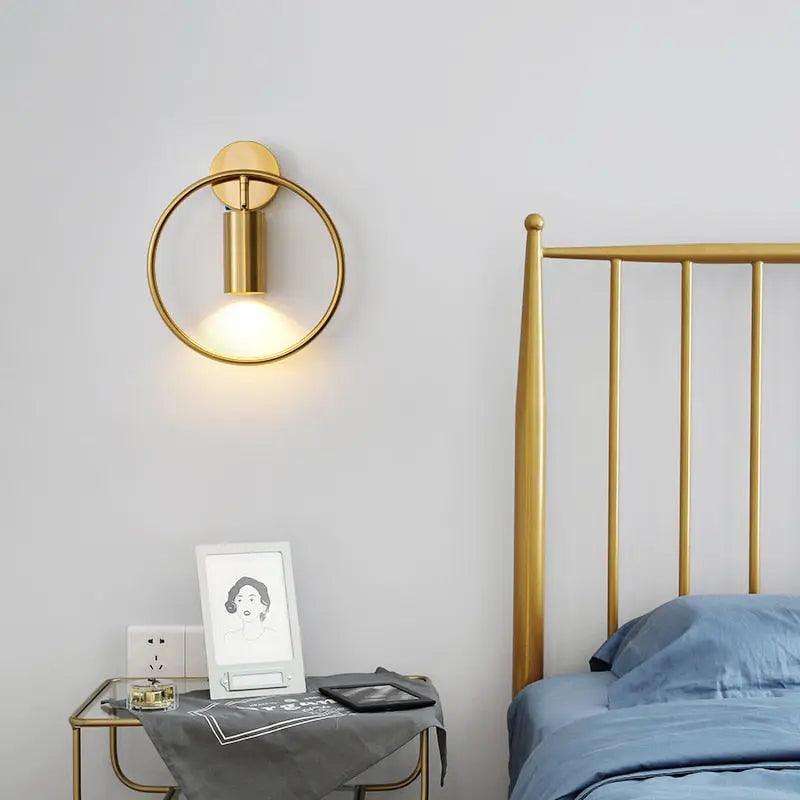 Benthe gold post-modern wall sconce on a white wall in a living room