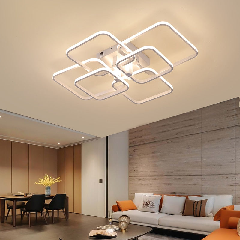 Quadrilateral geometric LED ring chandelier in white, illuminated in a living room with high ceilings