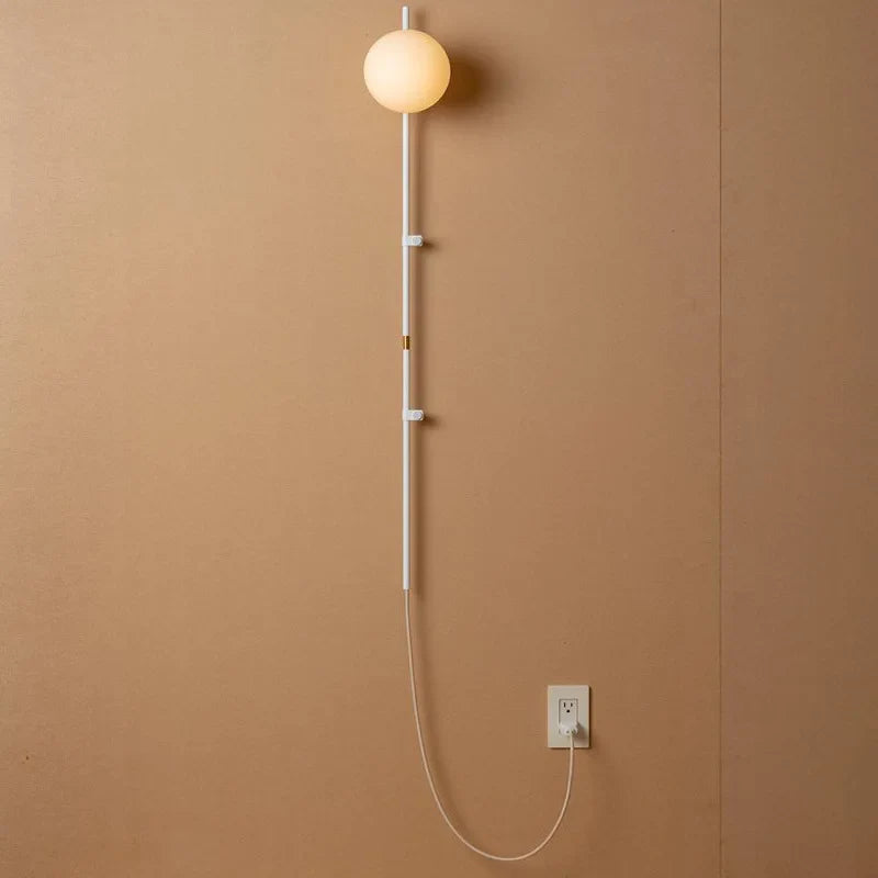 Sol Nordic plug-in wall sconce in black mounted in a living room beside a sofa