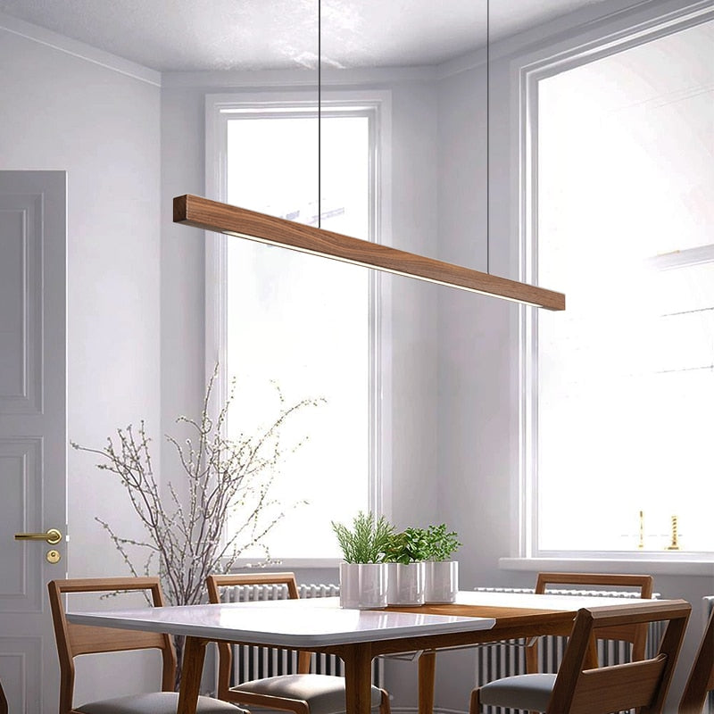 Lindö pine wood dining pendant light hanging low above a long dining table in a Nordic interior