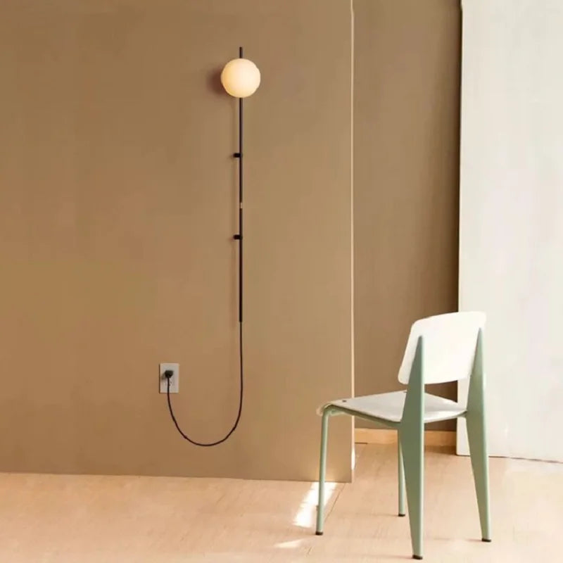 Sol Nordic plug-in wall sconce in black mounted in a living room beside a sofa