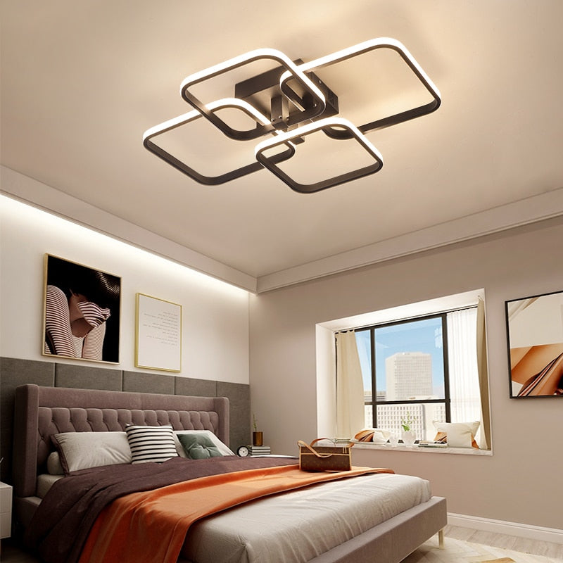 Quadrilateral geometric LED ring chandelier in white, illuminated in a living room with high ceilings