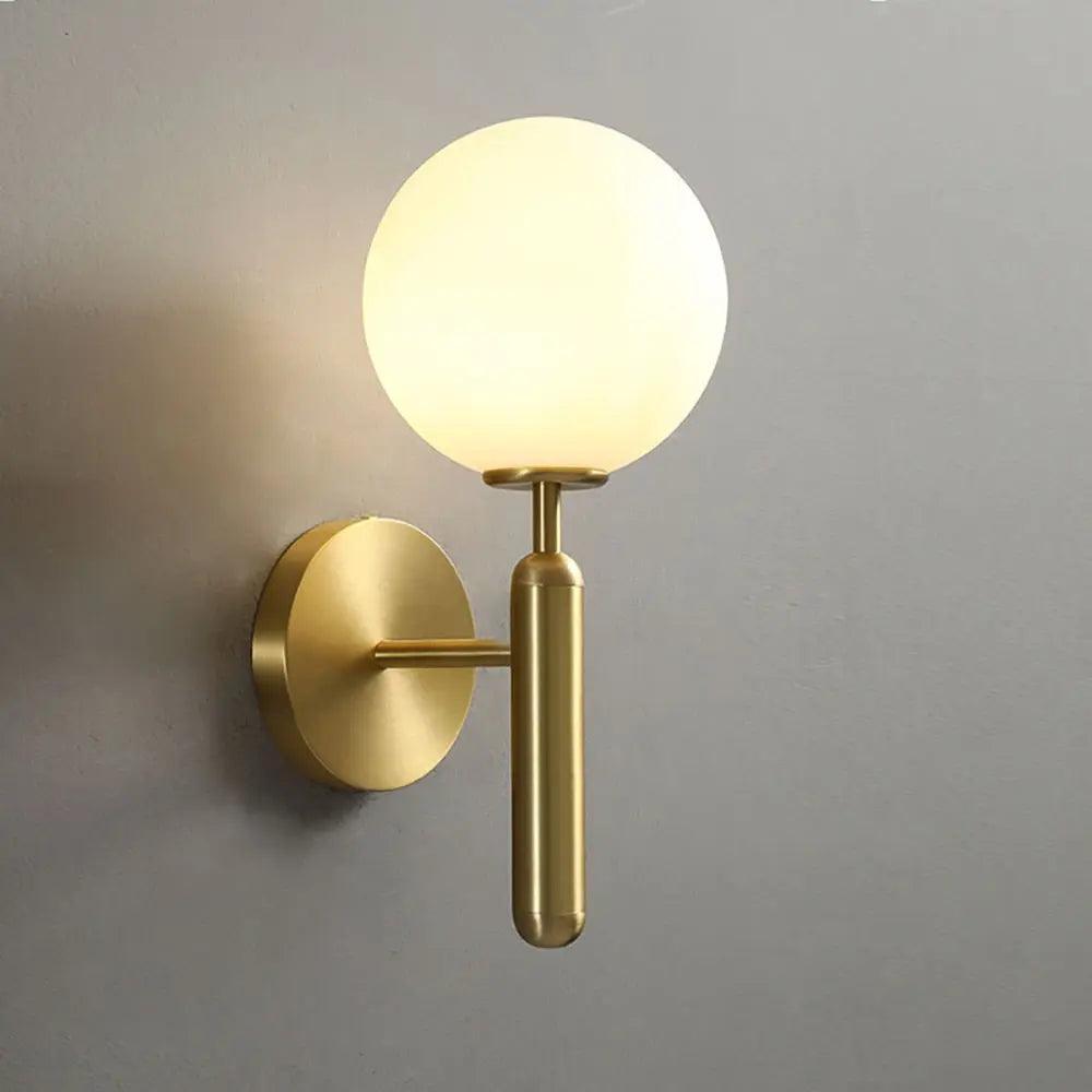 Mynte luxury gold wall sconce with marble base and milk glass shade in a bedroom