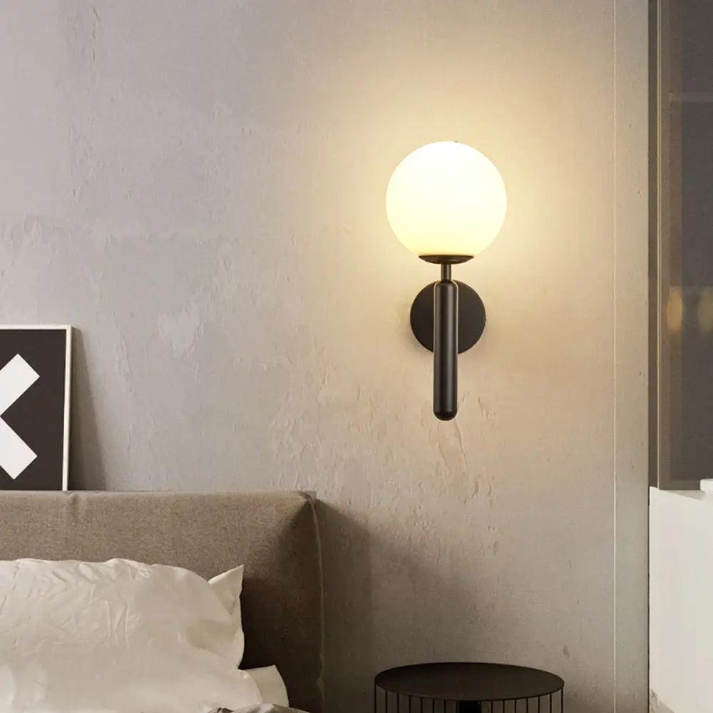 Mynte luxury gold wall sconce with marble base and milk glass shade in a bedroom