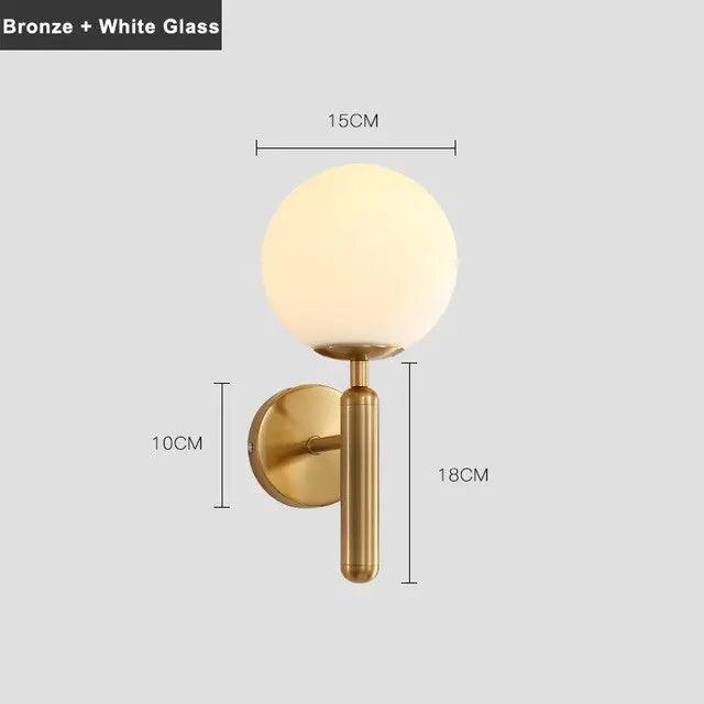 Mynte luxury gold wall sconce with marble base and milk glass shade in a bedroom