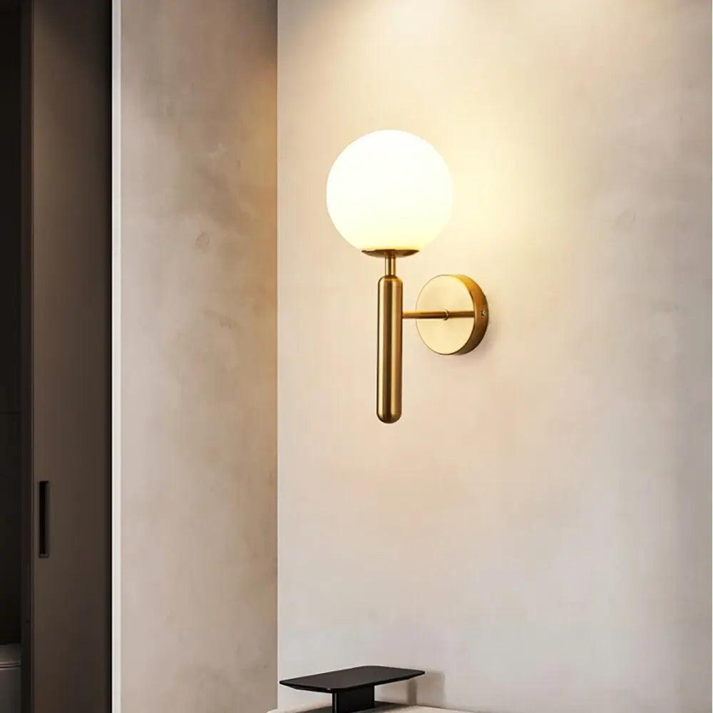 Mynte luxury gold wall sconce with marble base and milk glass shade in a bedroom