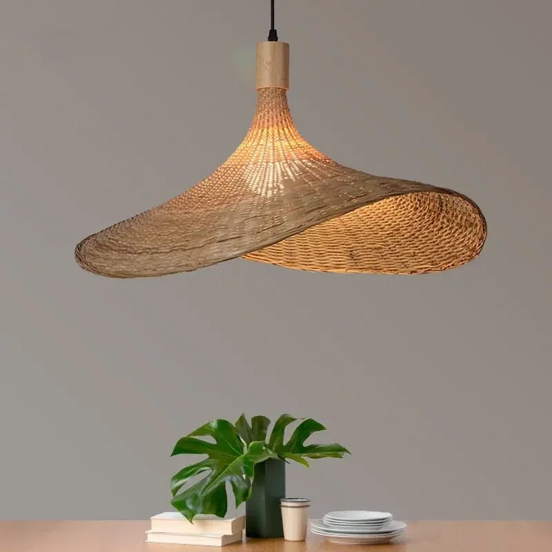 Wren handcrafted woven bamboo pendant light hanging above a wooden dining table in a warm interior