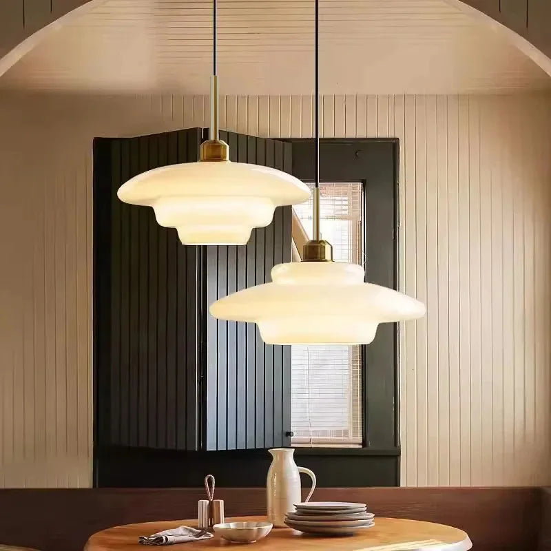 Opal milk glass pendant light hanging above a dining table, casting a soft warm glow