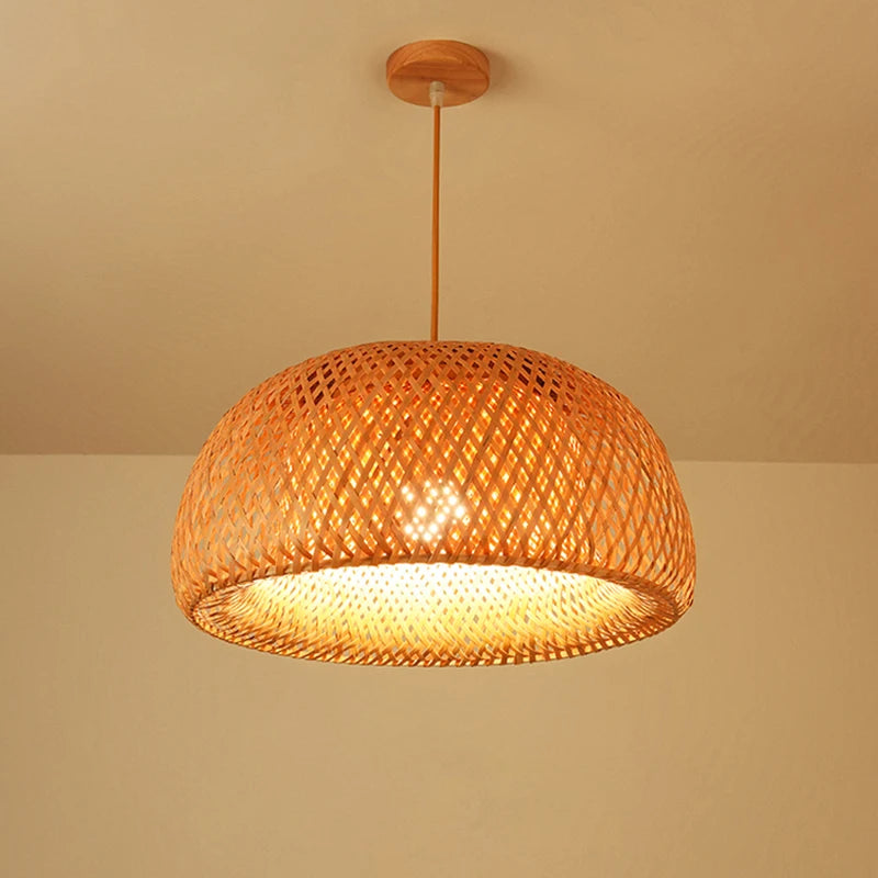 Wren handcrafted woven bamboo pendant light hanging above a wooden dining table in a warm interior