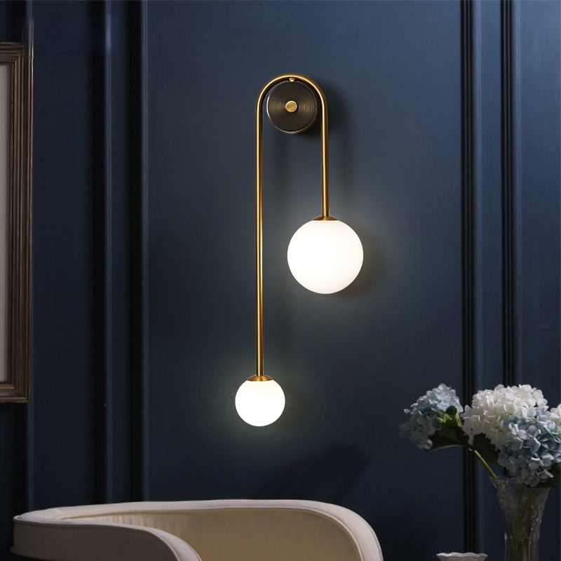 Amalia twin-arm gold Nordic wall sconce with white glass shades flanking a dining room mirror