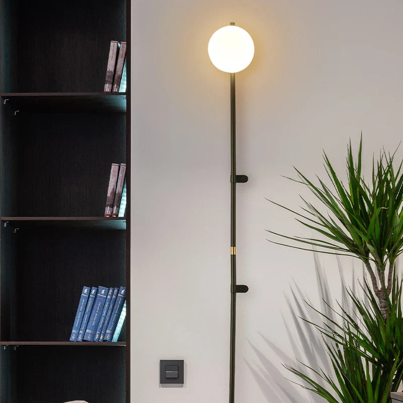 Sol Nordic plug-in wall sconce in black mounted in a living room beside a sofa