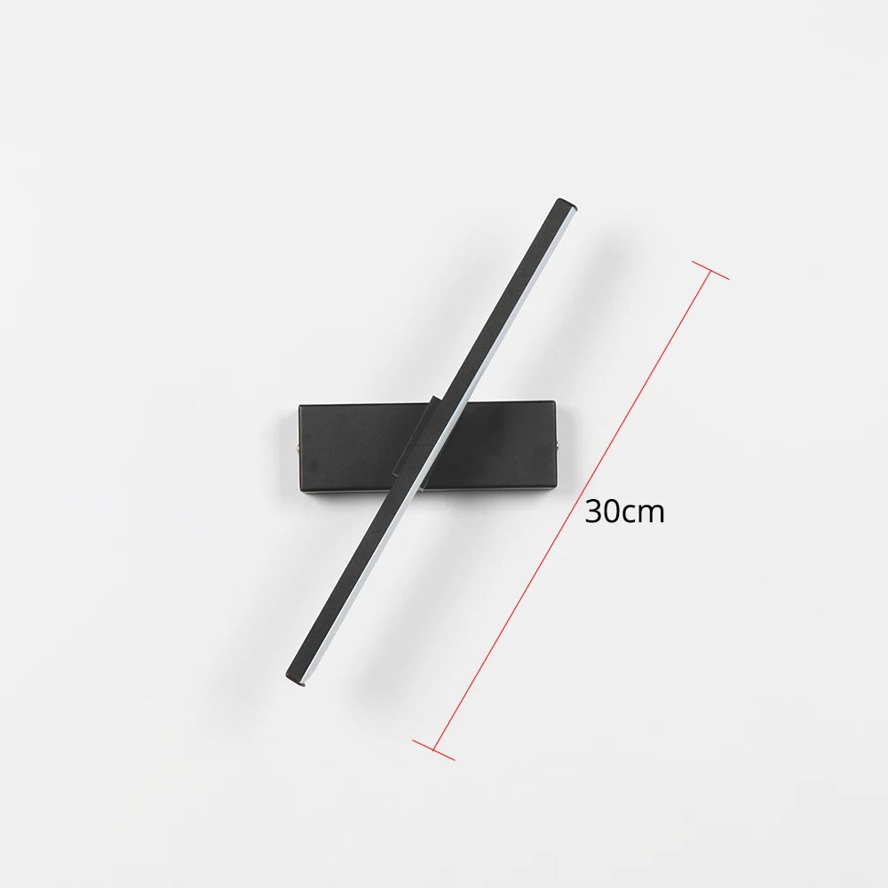 Arc 330-degree adjustable LED bedside wall lamp in black aluminium beside a bed with open book