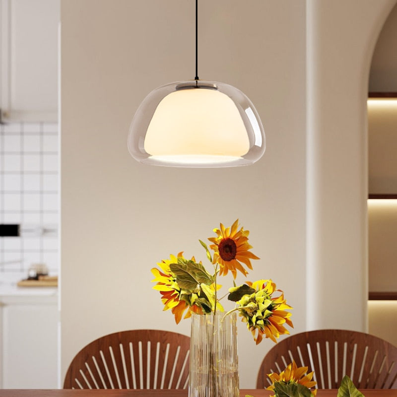Amba clear jelly globe pendant light with gold fitting hanging above a dining table