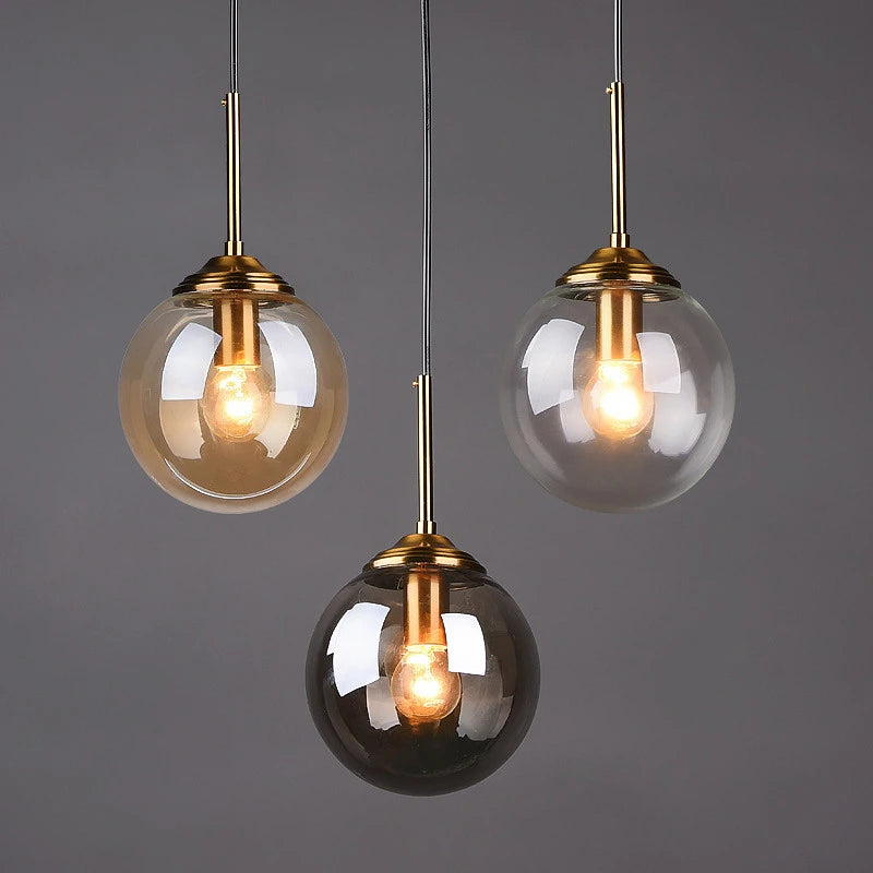 Orla amber glass and metal pendant light hanging above a bedside table in a Nordic-style bedroom