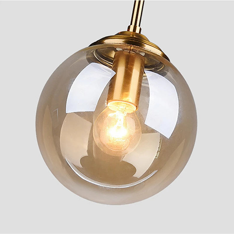 Orla amber glass and metal pendant light hanging above a bedside table in a Nordic-style bedroom