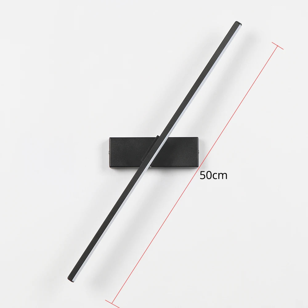 Arc 330-degree adjustable LED bedside wall lamp in black aluminium beside a bed with open book