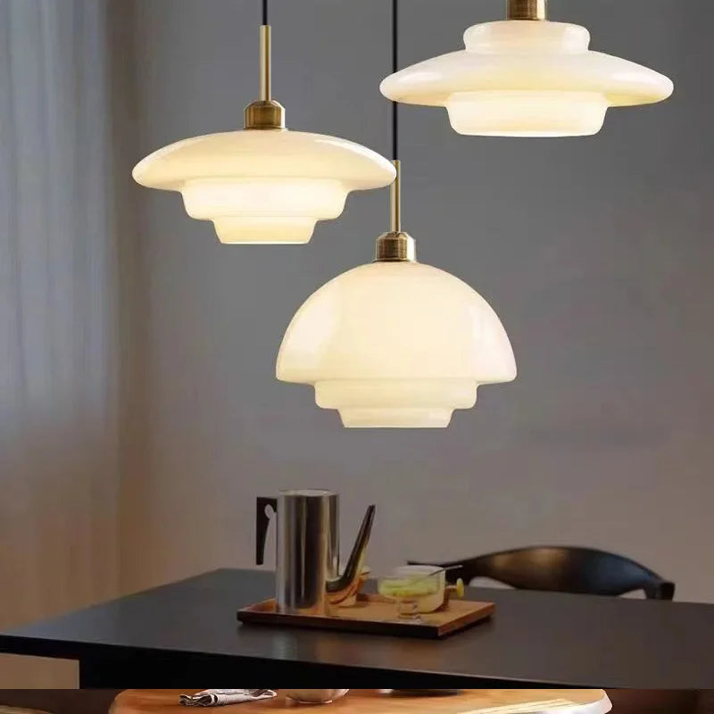 Opal milk glass pendant light hanging above a dining table, casting a soft warm glow