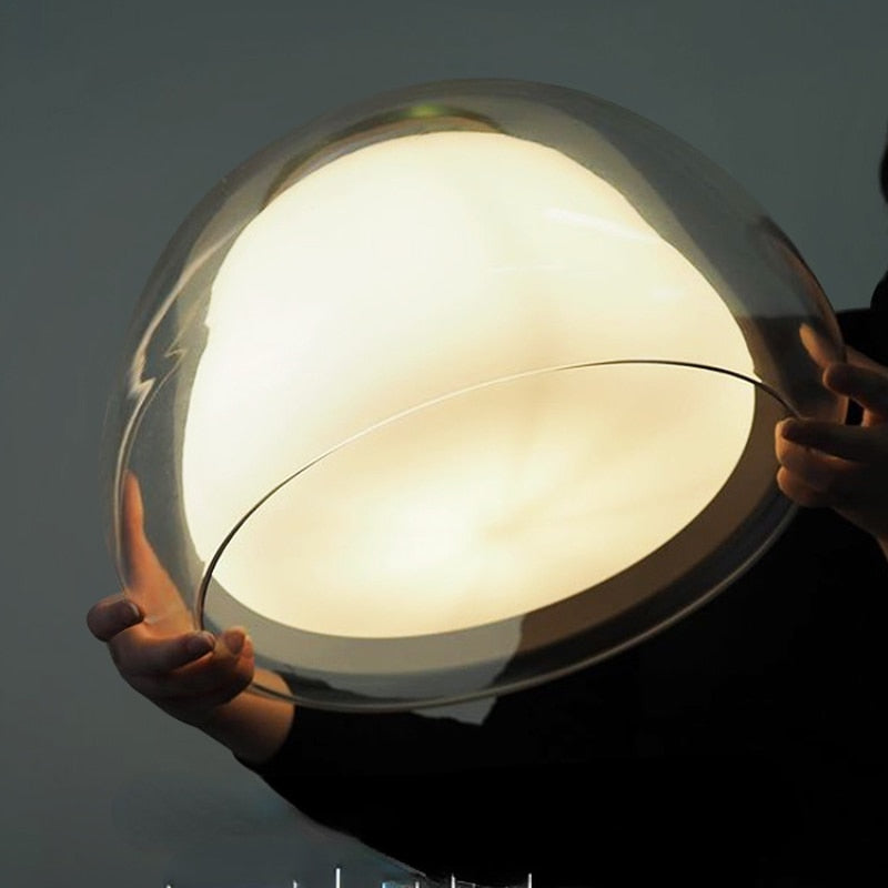 Amba clear jelly globe pendant light with gold fitting hanging above a dining table